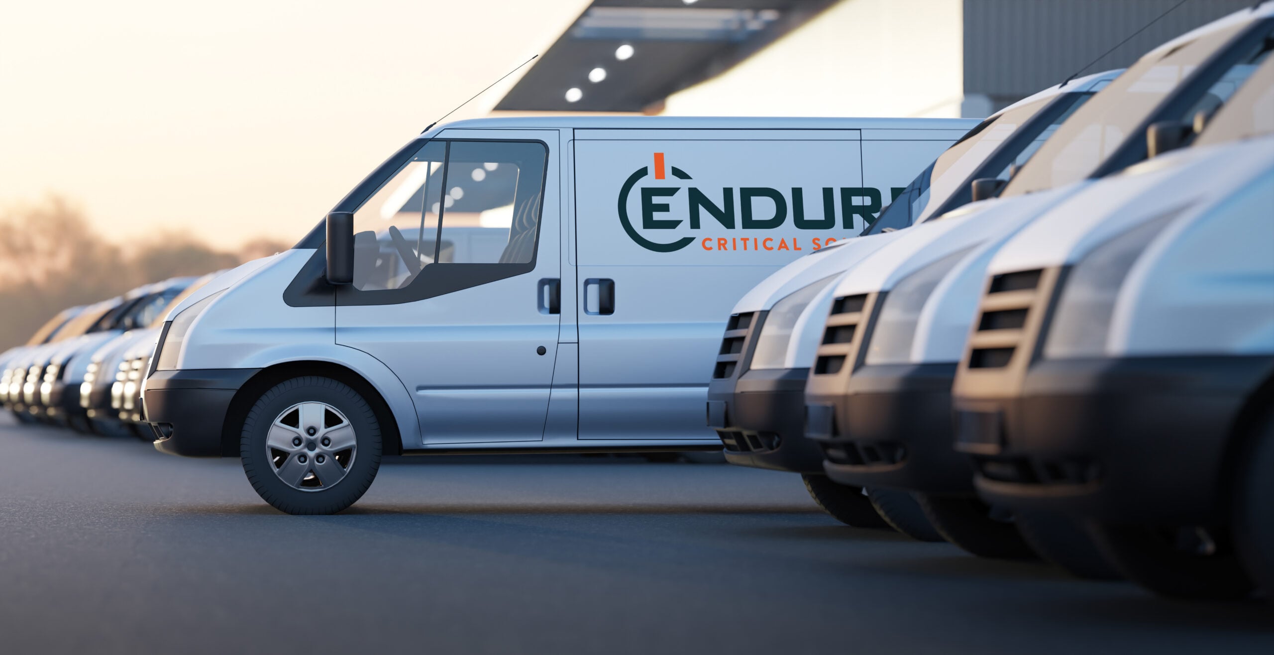 Silver van with "ENDURANCE CRITICAL S..." logo parked in a line with other vans.