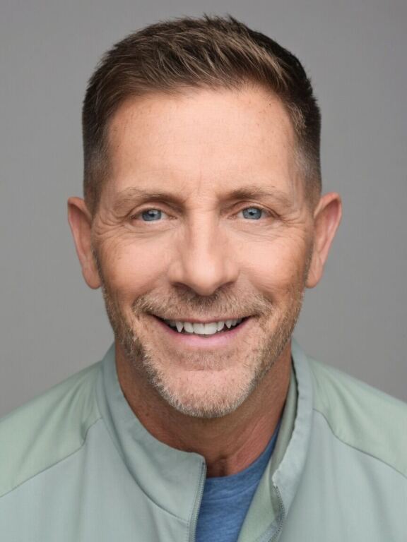 Man with blue eyes, short brown hair, and a light blue jacket smiling.